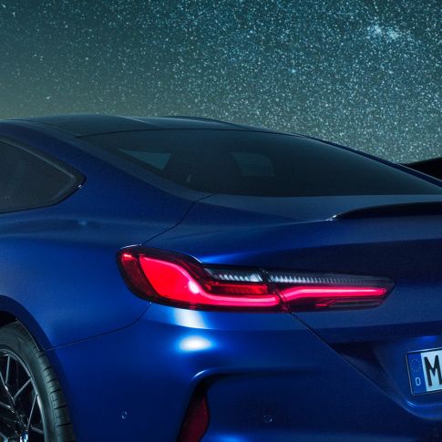 M rear spoiler BMW M8 Competition Coupé in Marina Bay Blue metallic, nightly close-up of shoulder section with M rear spoiler in Carbon.