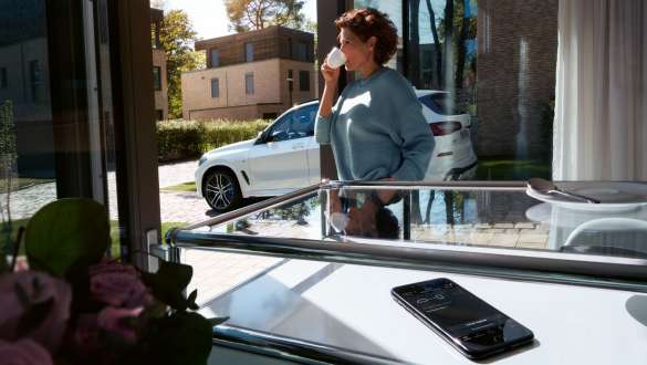 Woman drinking a cup of coffee while she updates the software of her BMW X5 via Remote Software Upgrade G05 2018