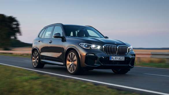 Plug-in hybrid BMW X5 xDrive45e G05 three-quarter front view driving on the street 