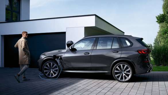 Plug-in hybrid BMW X5 xDrive45e G05 side view in front of garage with model