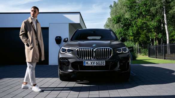 Plug-in hybrid BMW X5 xDrive45e G05 front view in front of garage with model
