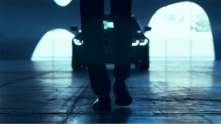 BMW 3 Series Saloon (G20), Front. View from behind of walking man in front of the BMW 3 Series Saloon (G20) on asphalt.