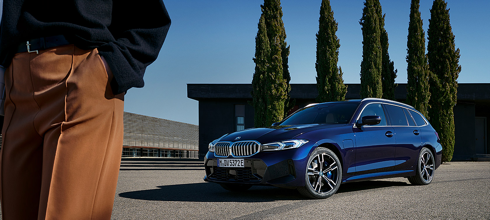 BMW 3 Series Touring LCI G21 Tansanit Blue II three-quarter front view standing in front of trees