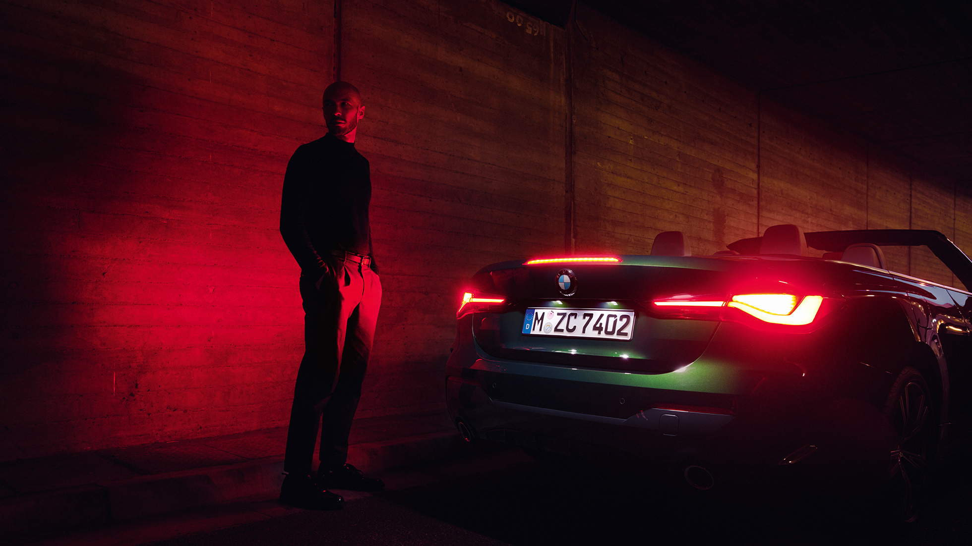 Three-quarter rear view with open softtop BMW 4 Series Convertible G23 2020 BMW 4 Series Convertible G23 2020 Sanremo Green metallic three-quarter rear view at night with open softtop
