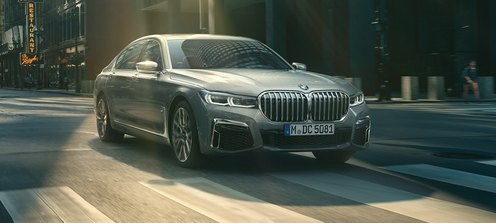 Grey BMW 7 Series Saloon driving, three-quarter front view Grey BMW 7 Series Saloon drives through the urban setting in the three-quarter front view