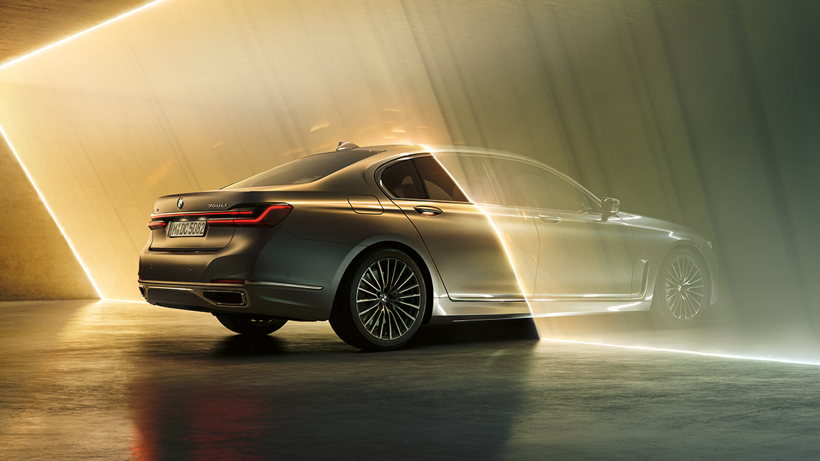 BMW 7 Series Saloon in Bernina Grey BMW 7 Series Saloon in Bernina Grey in three-quarter rear view surrounded by beam of light
