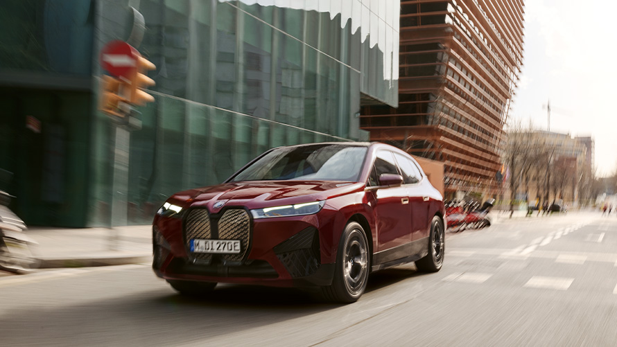 BMW iX i20 2021 electric SUV BMW iX xDrive50 Aventurin Red driving in urban sorroundings