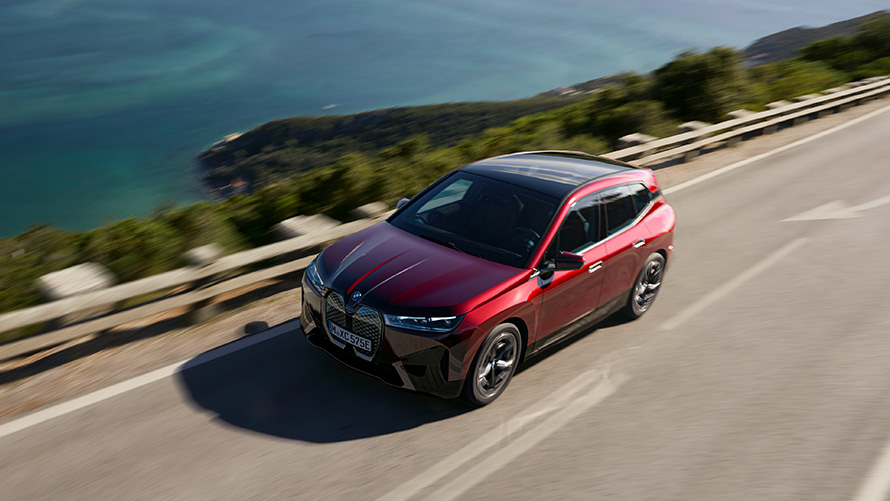 BMW iX i20 2021 electric SUV BMW iX xDrive50 Aventurin Red driving on a street performance