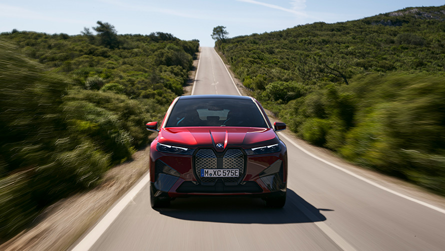 BMW iX i20 2021 electric SUV BMW iX xDrive50 Aventurin Red driving on a street range