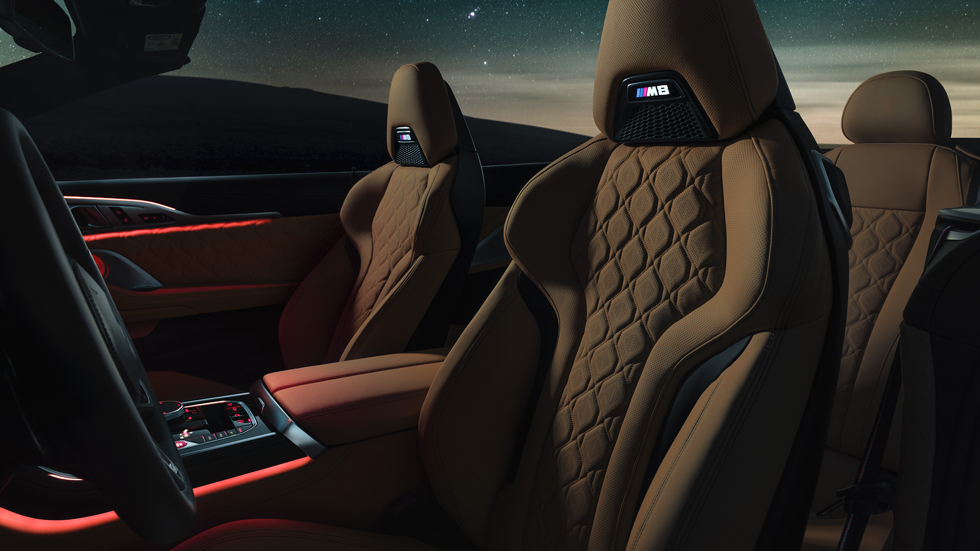 M Sport seats in leather 'Merino'. BMW M8 Competition Convertible with open softtop ander starry sky, interior with M Sport seats in leather 'Merino' and red ambient light.