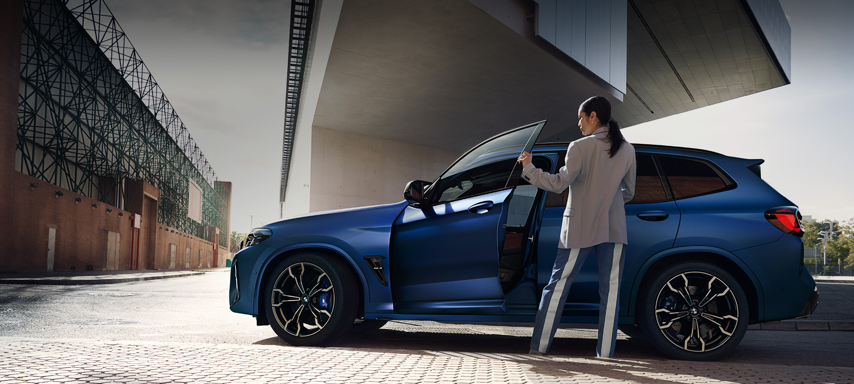 BMW X3 M Competition F97 LCI Facelift 2021 side view standing BMW X3 M Competition F97 LCI Facelift 2021 BMW Individual Frozen Portimao Blue metallic side view standing with open door and female model