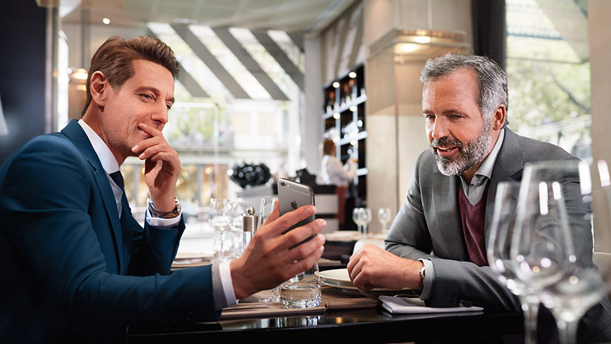 Manage your favourite Locations Two men in restaurant using feature „Manage your favourite Locations“ on smartphone