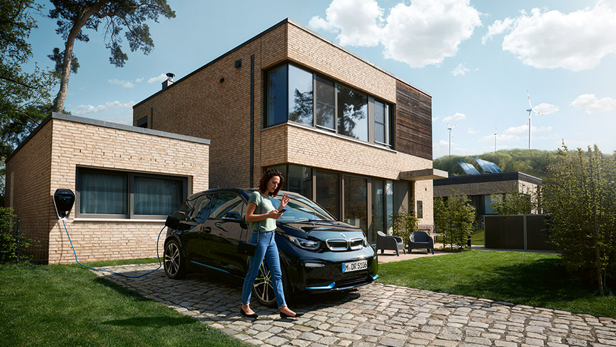BMW Digital Charging Service. Woman outside house using BMW Digital Charging Service.
