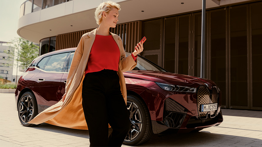Woman looking at phone next to BMW Woman looking at phone next to BMW