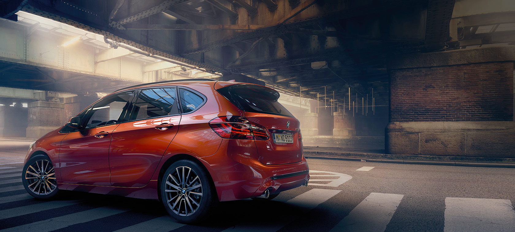 Three-quarter rear view BMW 2 Series Active Tourer 220i BMW 2 Series Active Tourer 220i F45 Facelift 2018 Sunset Orange metallic three-quarter rear view driving on the road