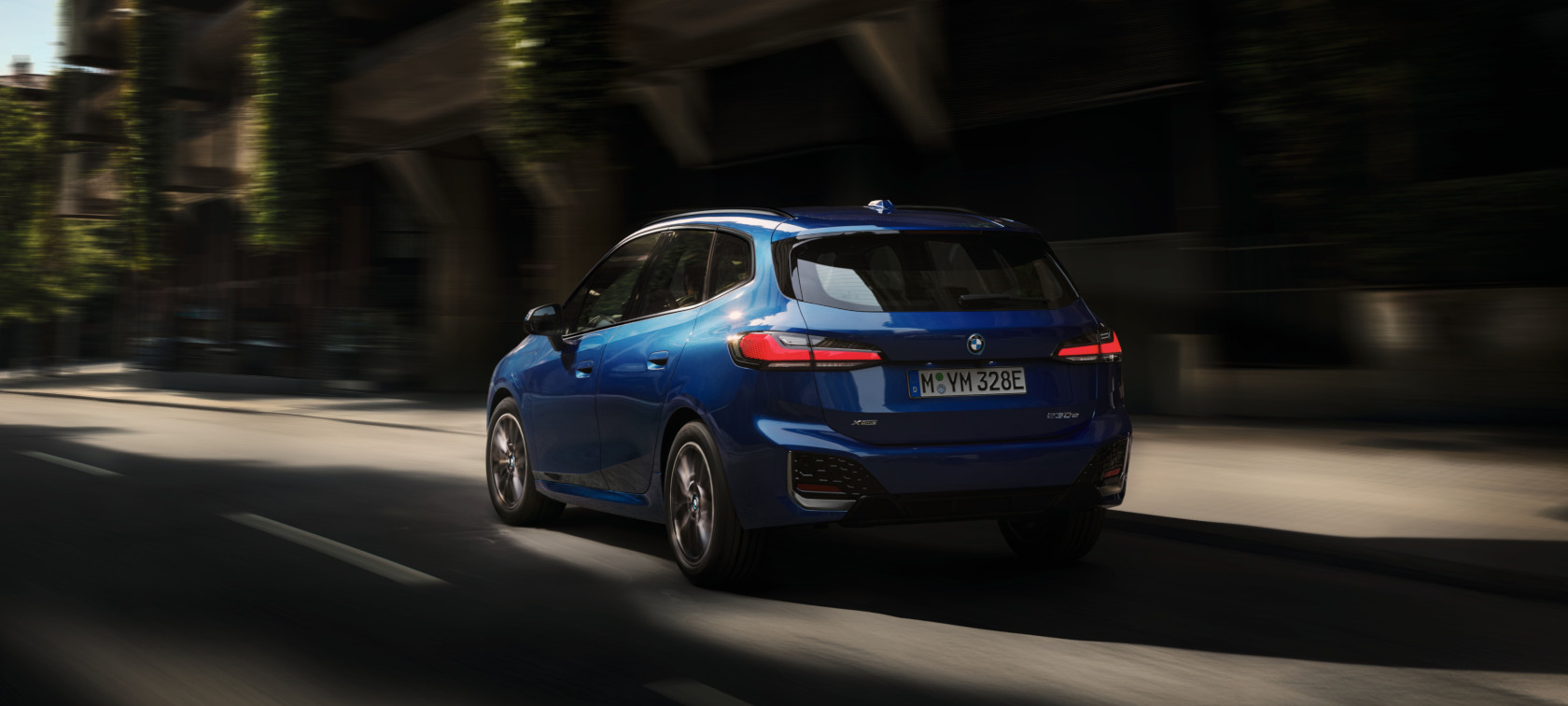 BMW 2 Series Active Tourer 230e plug-in hybrid U06 2021 M Portimao Blue metallic three-quarter rear view driving in the city