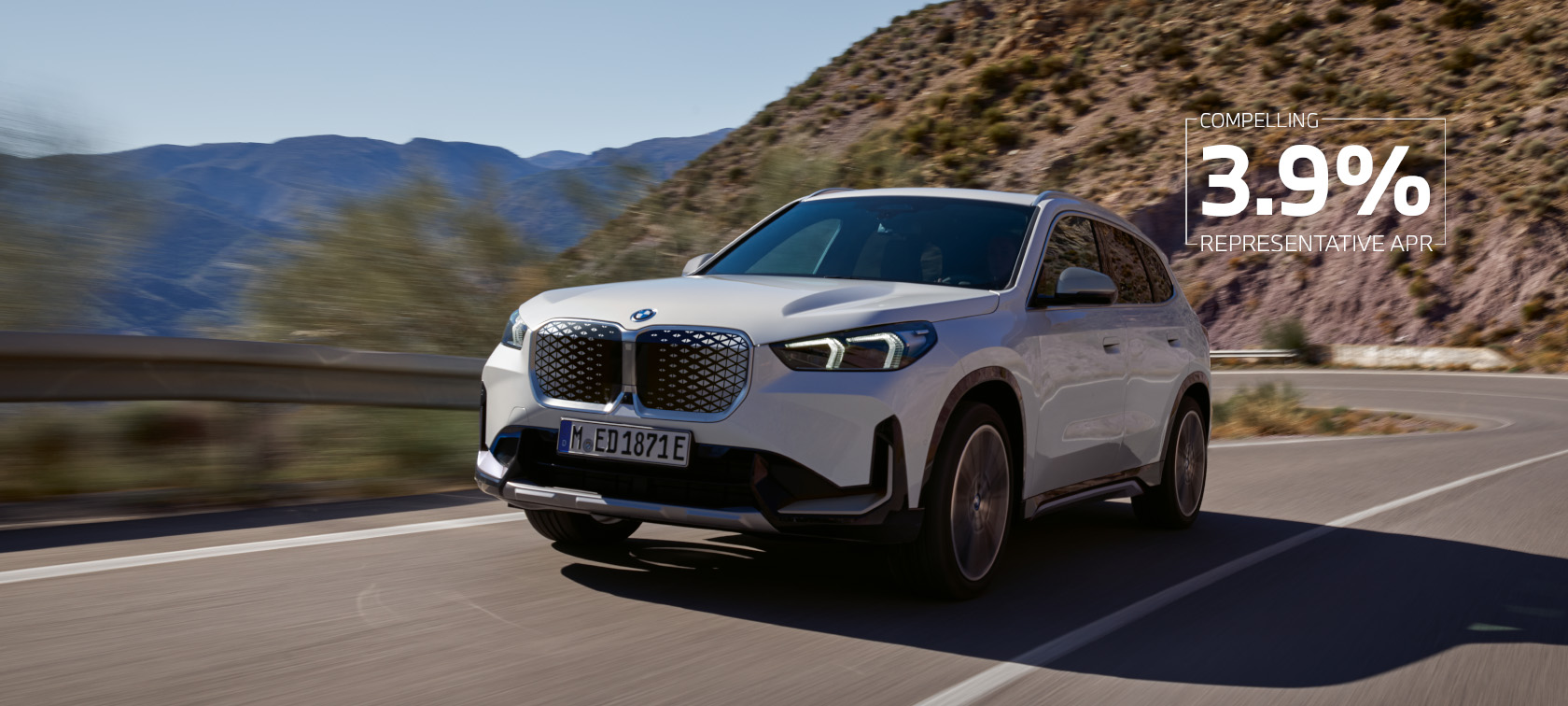 BMW iX1 U11 BEV 2022 Mineral White metallic three quarter front view serpentine mountain road driving