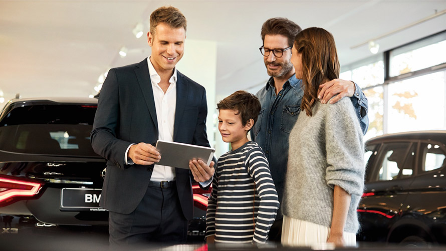 BMW representative with family showing Finance options on tablet BMW representative with family showing Finance options on tablet