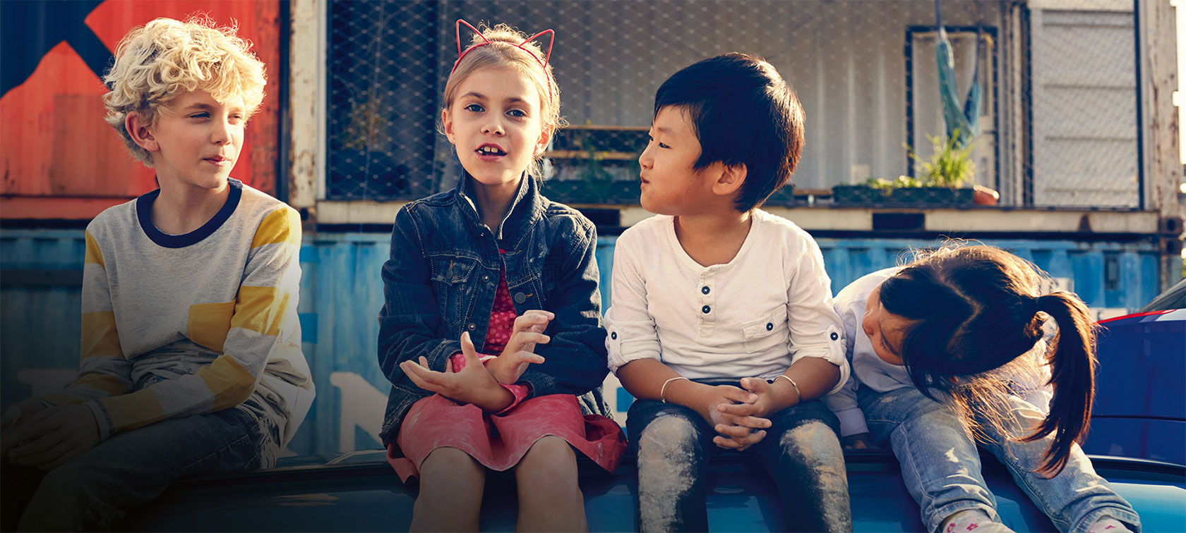 BMW Group Education. Kids sitting on wall.