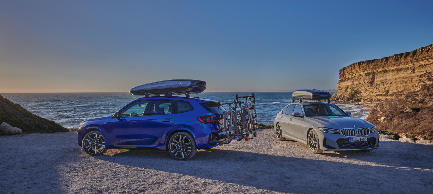 Original BMW Accessories for Spring and Summer BMW X1 U11 Original BMW Accessories for Spring and Summer BMW X1 U11 standing on sand in front of a coast with 2 people